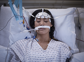 Top view of sleeping patient intubated in hospital bed.