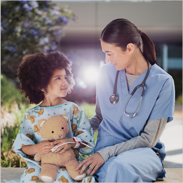 Médico con un estetoscopio sentado al aire libre con un niño que sostiene un osito de peluche y usa un sensor Masimo. 